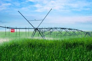 Sistema de irrigação por pivô central em campo agrícola verdejante para otimização da produção de alimentos.
