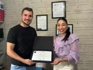 Homem e mulher sorrindo segurando certificado de conquista em ambiente de escritório, celebrando sucesso profissional em sustentabilidade e meio ambiente.