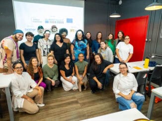 Professores e participantes em workshop de sustentabilidade, em ambiente moderno de treinamento, promovendo capacitação em ambientalismo e práticas sustentáveis.