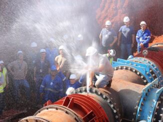 Manutenção e inspeção de tubulação de água ou petróleo com equipe de engenheiros e técnicos usando capacetes de segurança na obra.