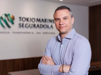 Gerente em frente ao logo da Tokio Marine Seguradora, simbolizando segurança, confiança e serviços de seguros corporativos.