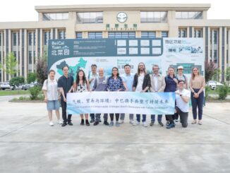 Colaboradores segurando banner em frente ao Hotel Belmonte durante evento de sustentabilidade e comércio ecológico, promovendo práticas sustentáveis e inovação ambiental na região.