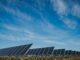 Painel solar em campo aberto com céu azul, energia renovável solar, instalação de painéis solares, sustentabilidade ambiental, fonte de energia limpa, ambiental mercantil, energia solar para negócios e residências.