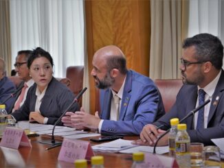 Profissionais em reunião de negócios ou conferência ambiental, discutindo estratégias sustentáveis e políticas de meio ambiente em ambiente corporativo formal.