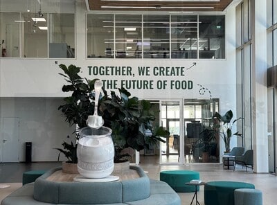 Ambiente de escritório moderno com decoração contemporânea, plantas verdes e iluminação natural, promovendo um ambiente profissional sustentável e inovador.