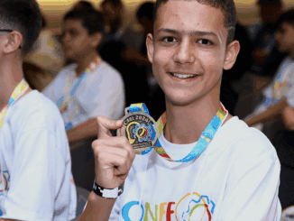 Estudante sorridente com medalha em mãos, participando de evento educacional sobre sustentabilidade e meio ambiente, promovido pela Ambiental Mercantil.