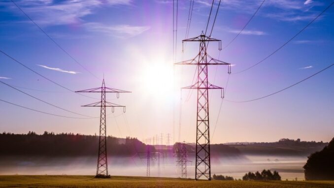 Linhas de transmissão de energia elétrica ao nascer do sol, representando infraestrutura de energia sustentável e geração de eletricidade.