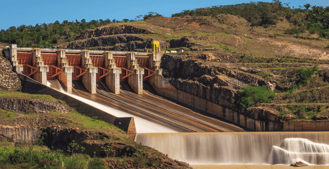 Alternativa de texto: Usina hidroelétrica com grande barragem e fluxo de água, gerando energia renovável e sustentável para a matriz energética brasileira.