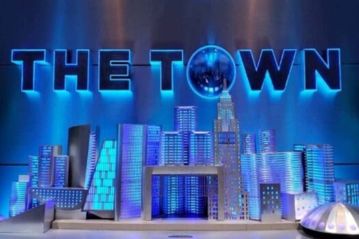 Imagens de uma réplica da cidade de Nova York com luzes azuis e o texto "THE TOWN" em destaque, ideal para eventos corporativos e ambientes tecnológicos.