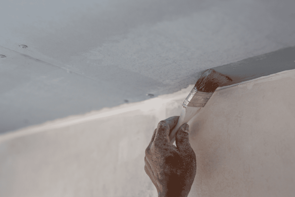 Removing popcorn ceiling texture with a paintbrush during renovation.