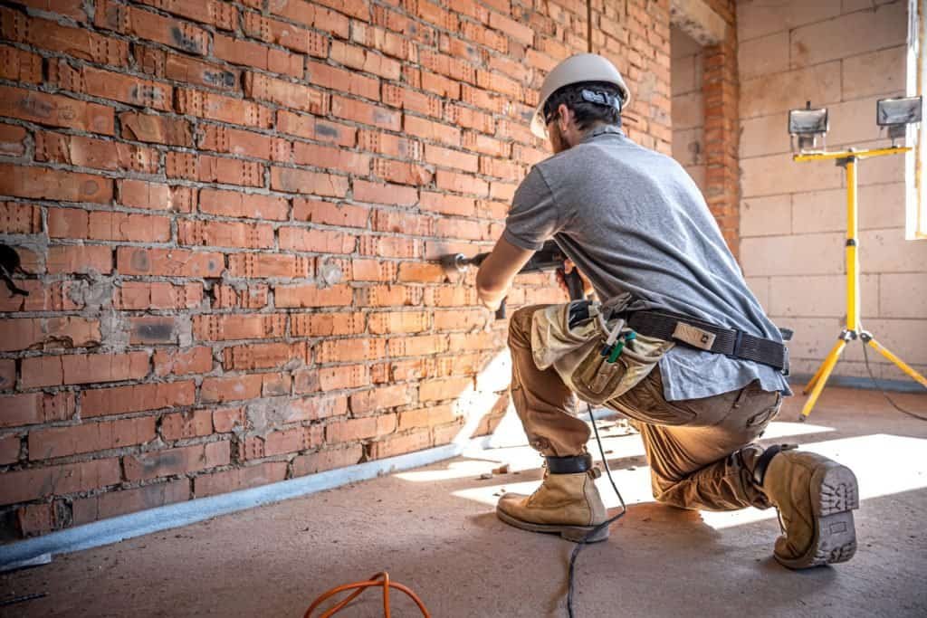Worker repairing brick wall during renovation project.