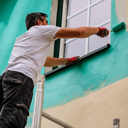 Painter applying teal exterior wall paint with roller brush.
