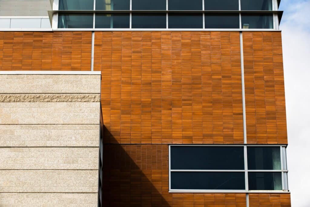 Contemporary building exterior featuring wood siding and large glass windows.