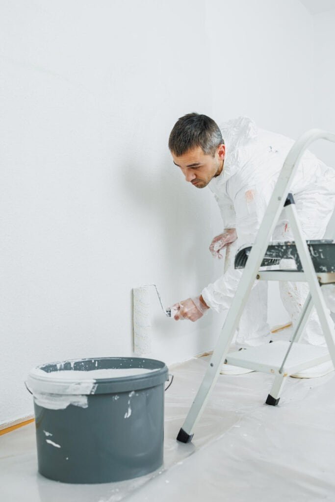 Man painting wall with roller brush in home interior.