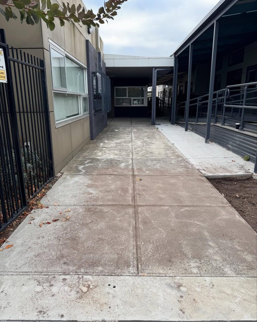 Worn concrete walkway at school before resurfacing showing surface wear and discoloration in Melbourne