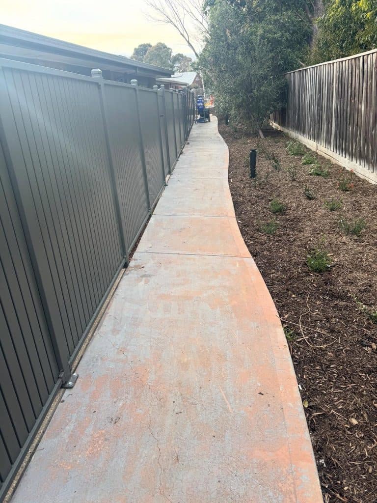 Stained and weathered concrete side path beside a timber fence before single colour resurfacing in Nunawading
