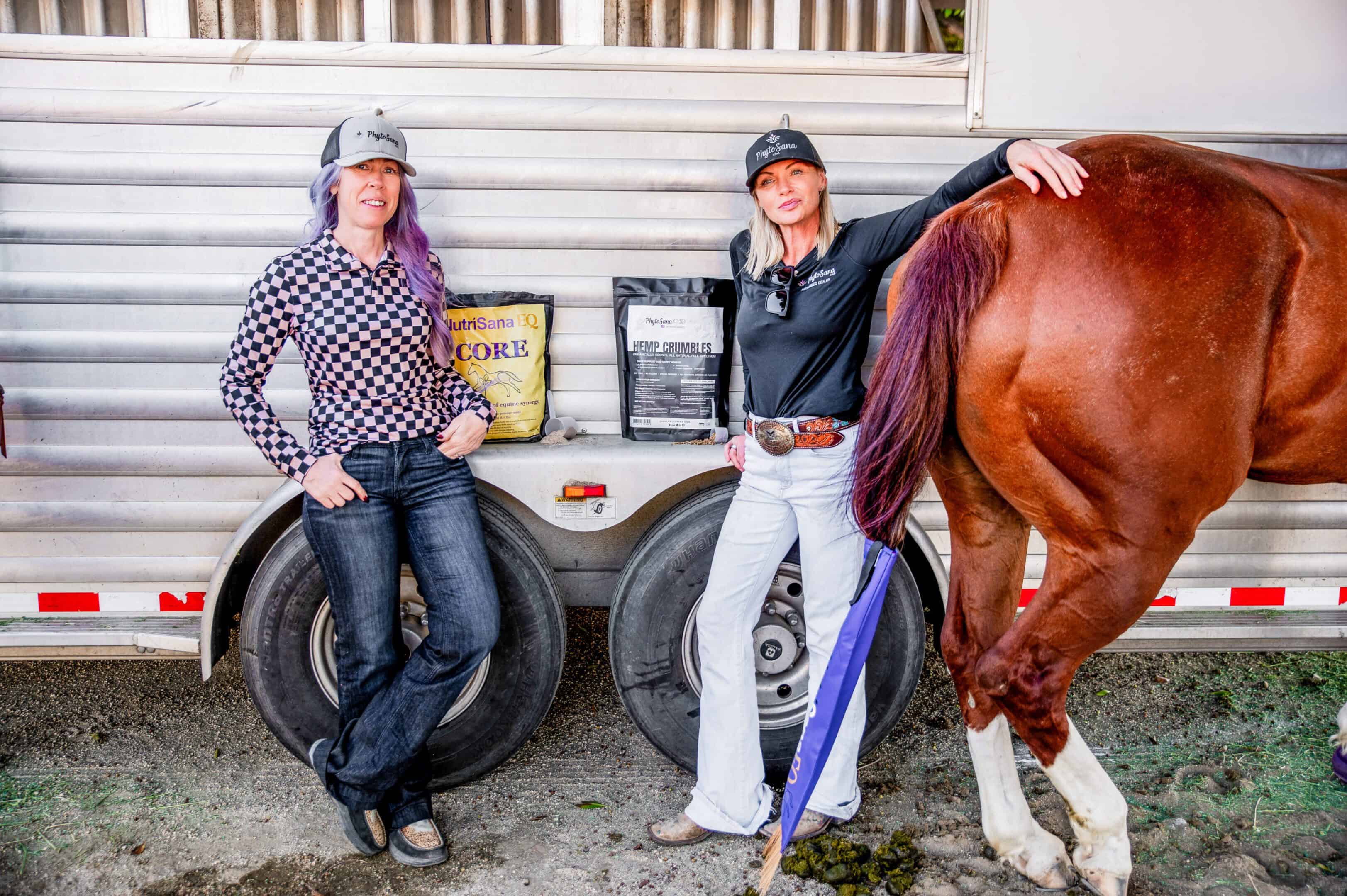 Two women with a horse and NutriSana EQ supplement products at a trailer.