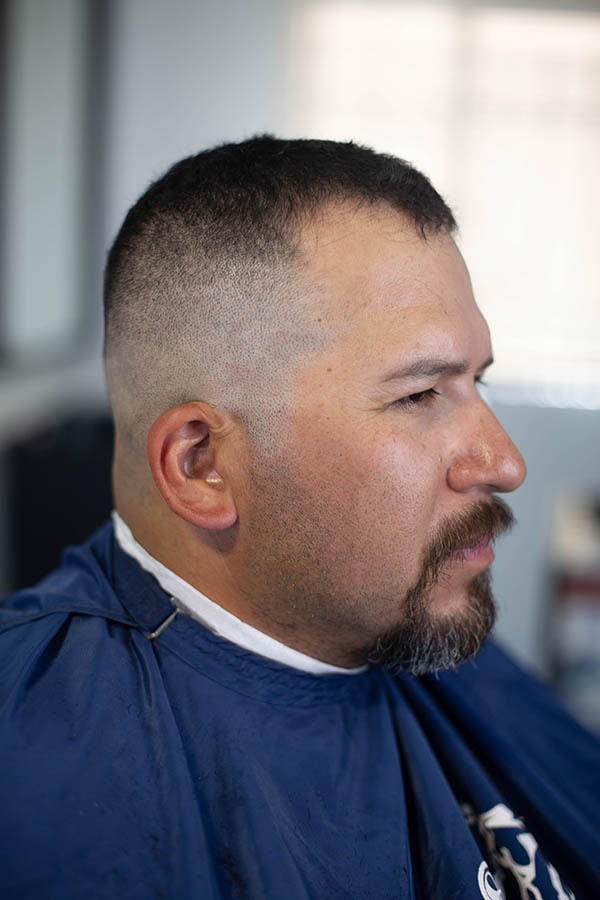 A side view of a man with a high and tight fade with short hair on top rocking a goatee
