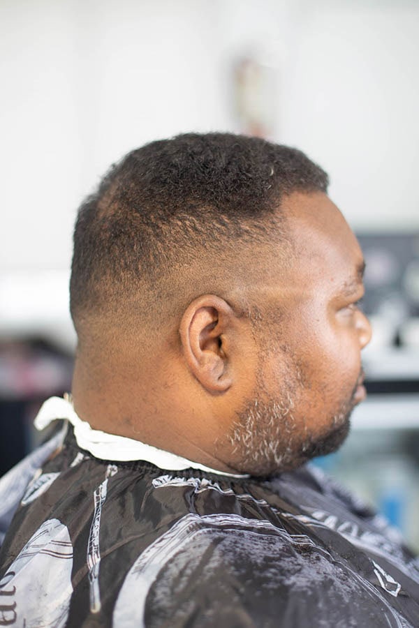 A side anlge of a man with curly hair with a mid fade and a beard done in Gardena ca 90249