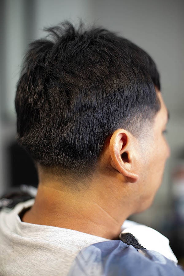 A back angle of a mans head with a taper haircut