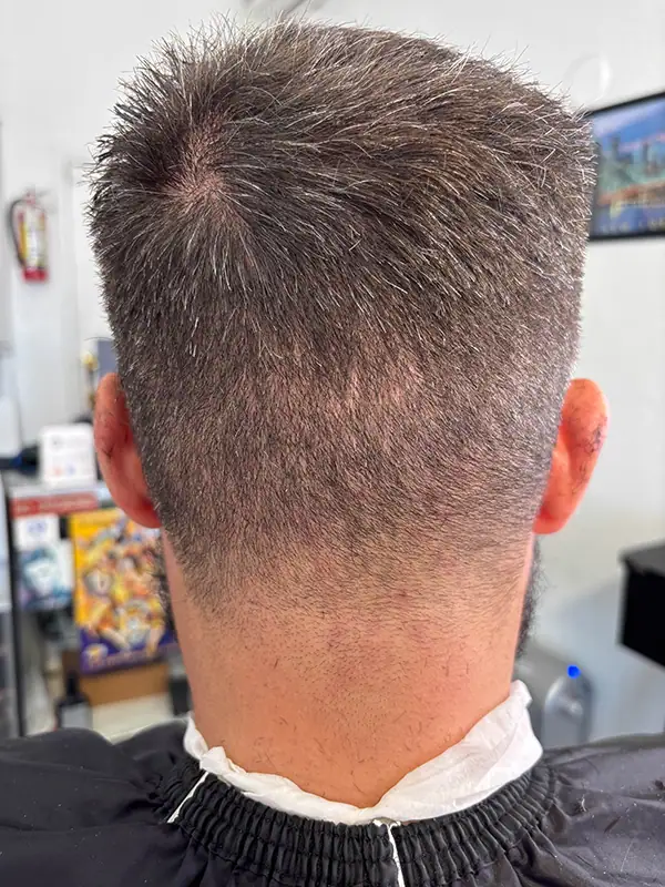 A man at a barbershop with a taper fade haircut