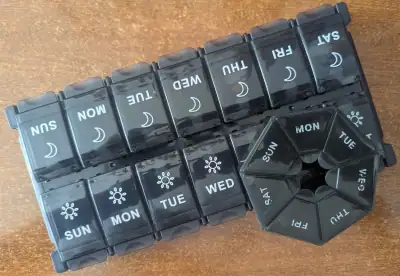 Two pillboxes -- one rectangular with morning and night, and one septagonal.