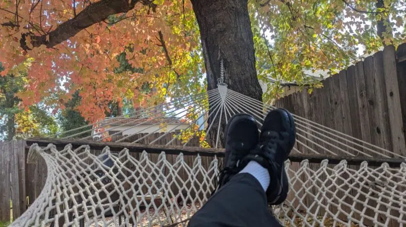 Feet up on a hammock, colorful autumn leaves