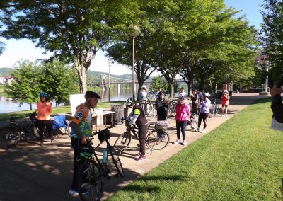 Group of cyclists and pedestrians enjoying the trail near the river.