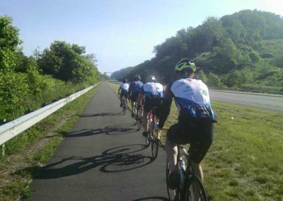 Group of cyclists riding on a scenic trail alongside a highway.