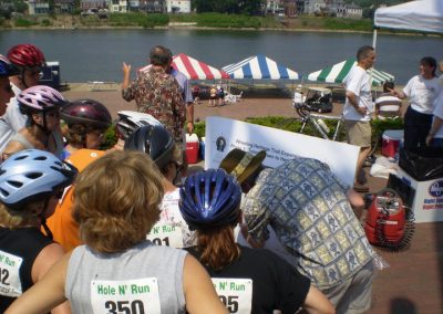Group of cyclists and event attendees by the river at Ohio Valley Trail.