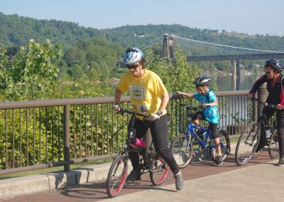 Cyclists enjoying a scenic trail with bridge views.