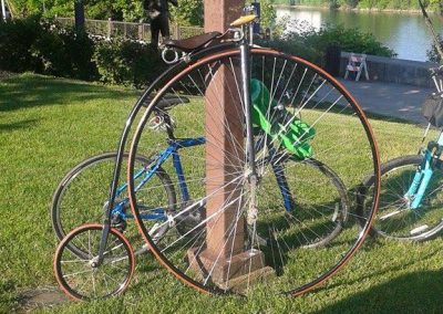 Classic penny-farthing bicycle leaning against a wooden post near Ohio River.
