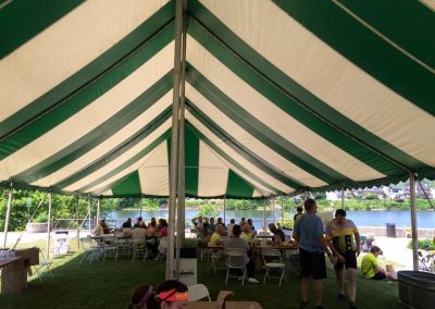 Under a large green and white striped tent by the river.