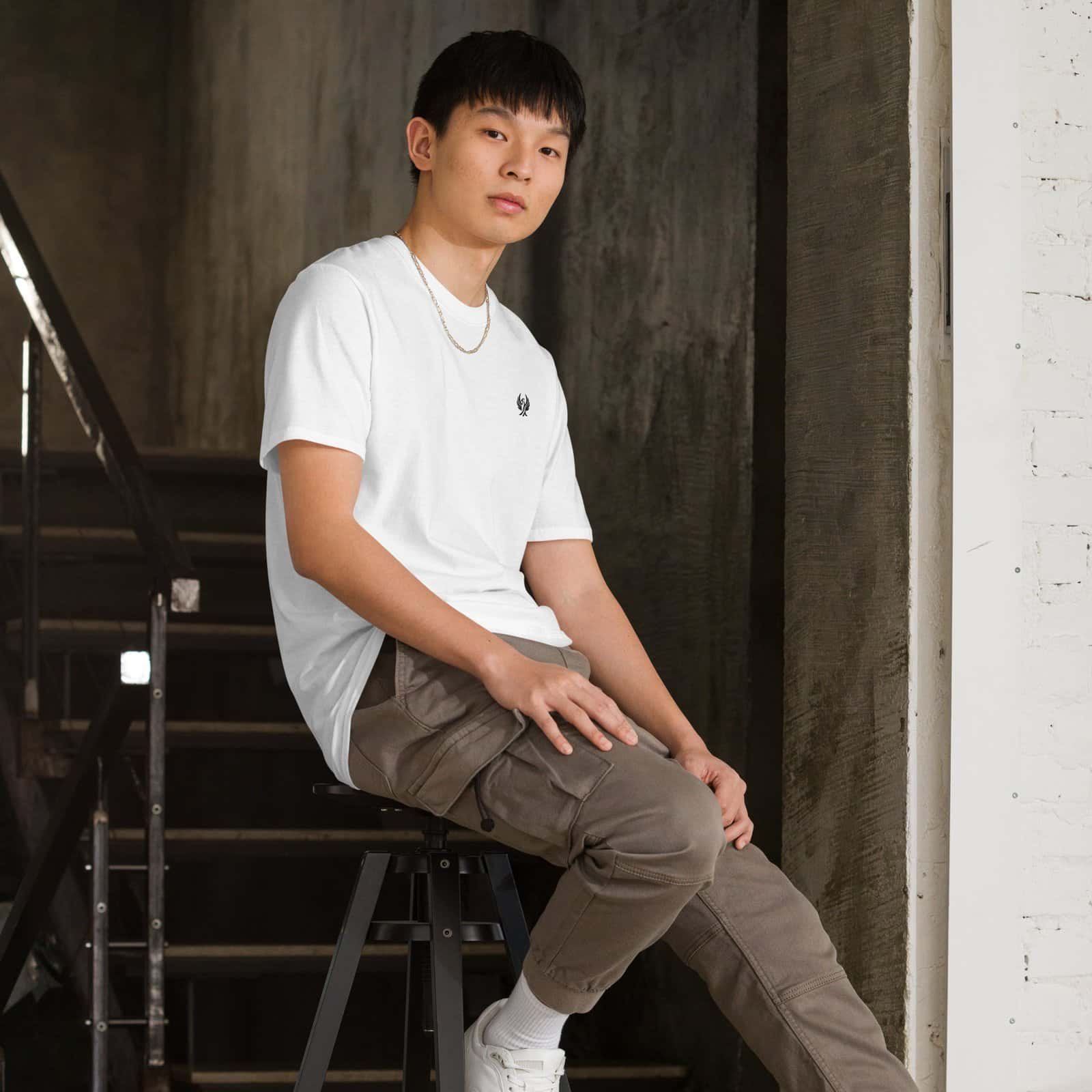 Jeune homme portant un T-shirt blanc cassé brodé noir, mettant en valeur l’art de porter l’infini avec style.