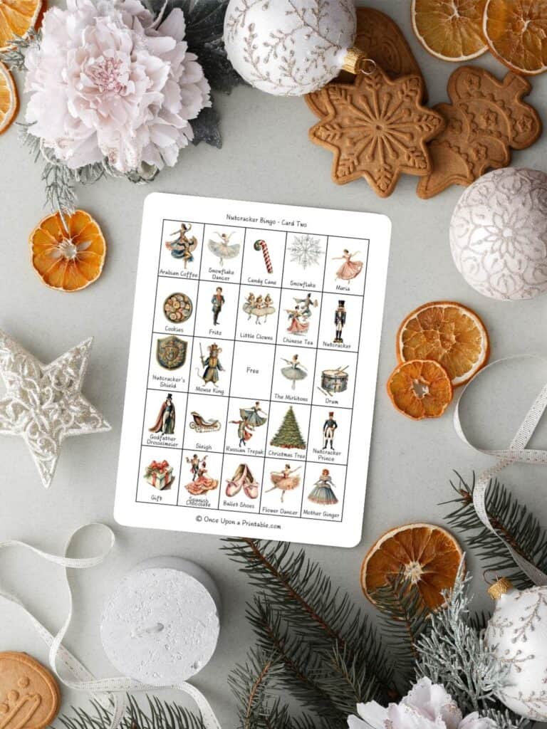Nutcracker themed bingo cards on a light background with christmas ornaments and dried oranges.