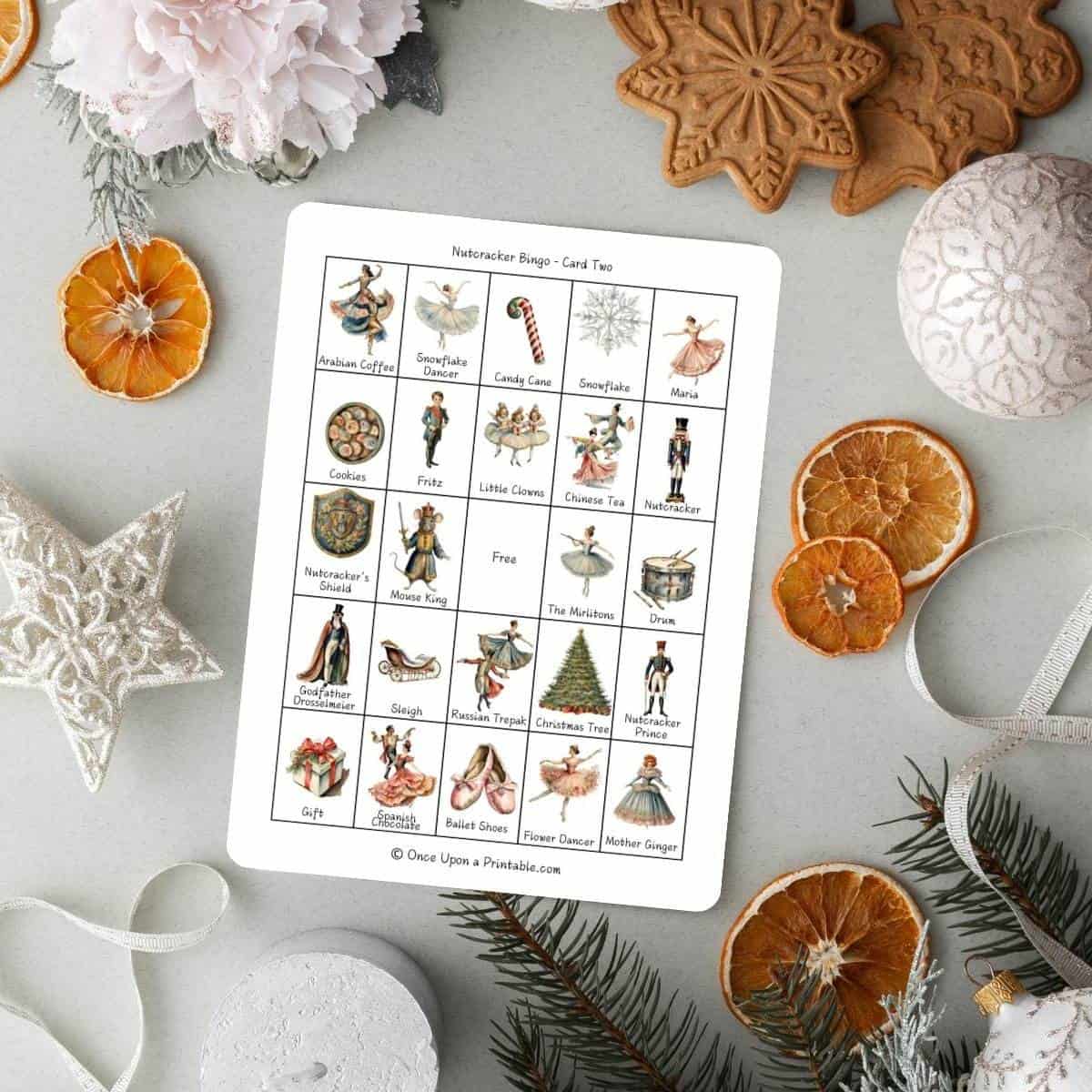 Nutcracker themed bingo cards on a light background with christmas ornaments and dried oranges.