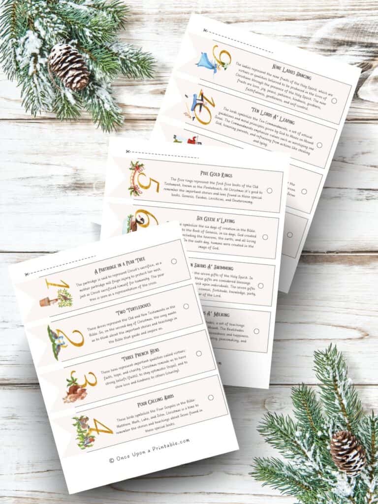 The 12 Days of Christmas garland cut outs in a pennant shape with beautiful pastel watercolor graphics displayed on a wooden background with green garland and pinecones.