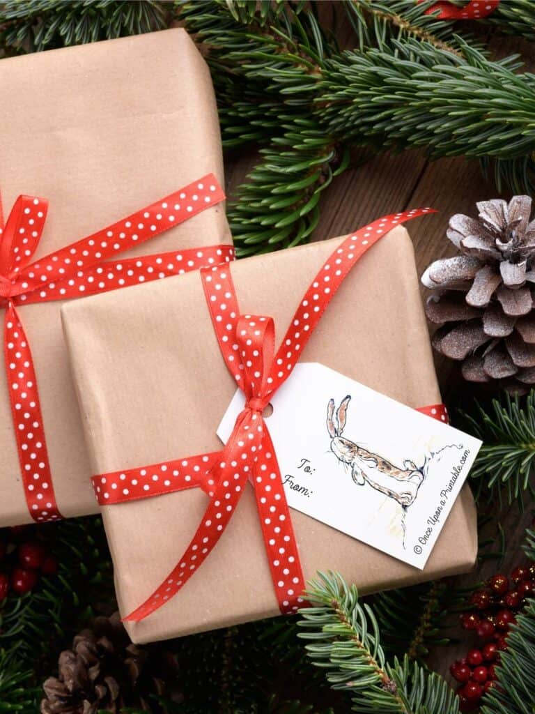 The Velveteen Rabbit gift tags on a brown paper package tied with a big satin red ribbon, pinecones, and red berries.
