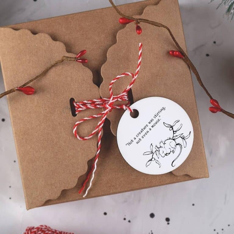 Vintage Illustrated Christmas gift tag displayed on a brown cardboard box tied with red and white string.