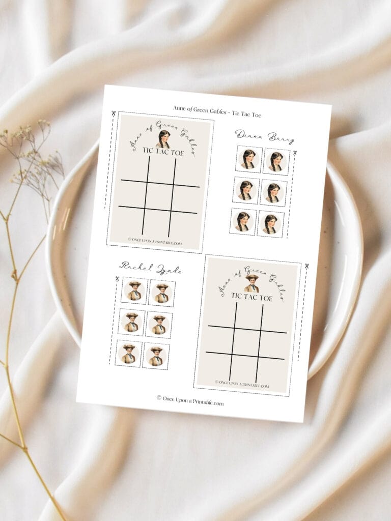 Diana Barry and Rachel Lynd tic tac toe cards printed out and laying on a ceramic plate on a cream table cloth with baby's breath flowers.