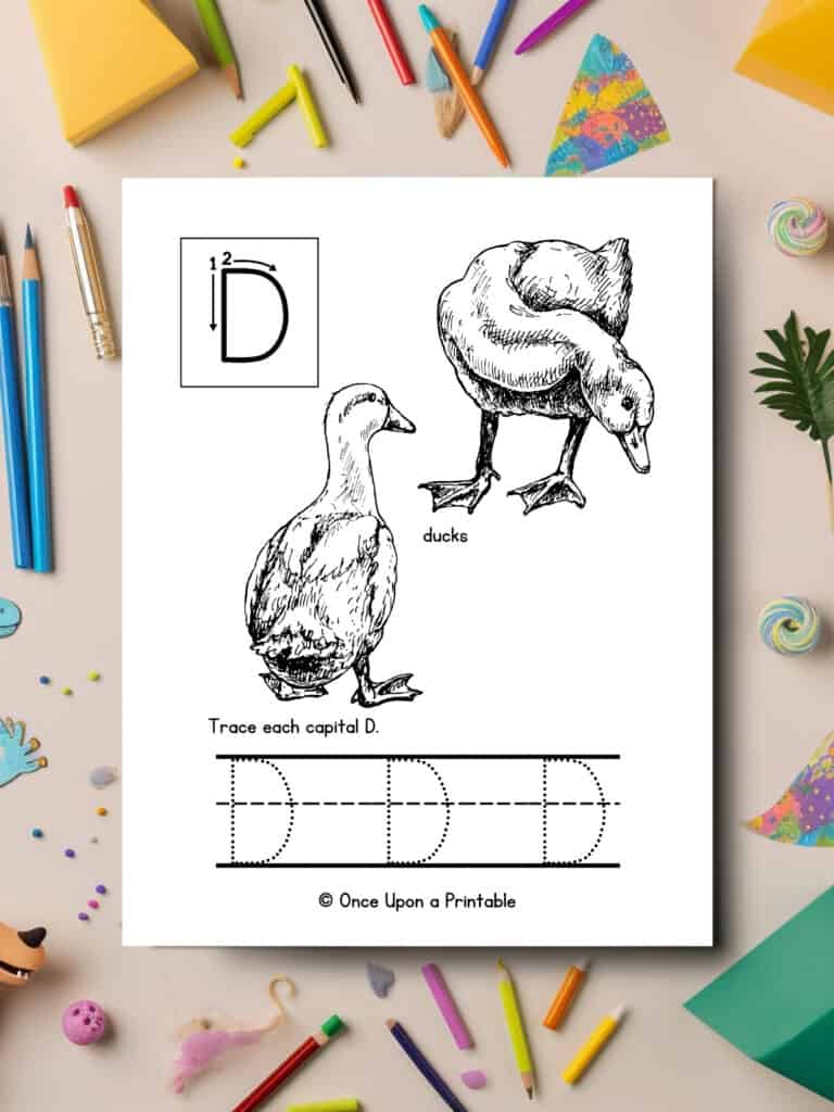 Letter D capital tracing and coloring page laying on a table with art supplies.