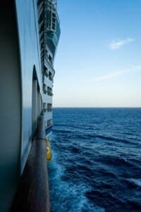 Side view of a cruise ship railing with ocean and clear sky in the background.