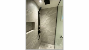 Modern basement bathroom renovation project with gray marble tiles and a standing shower with a shower niche