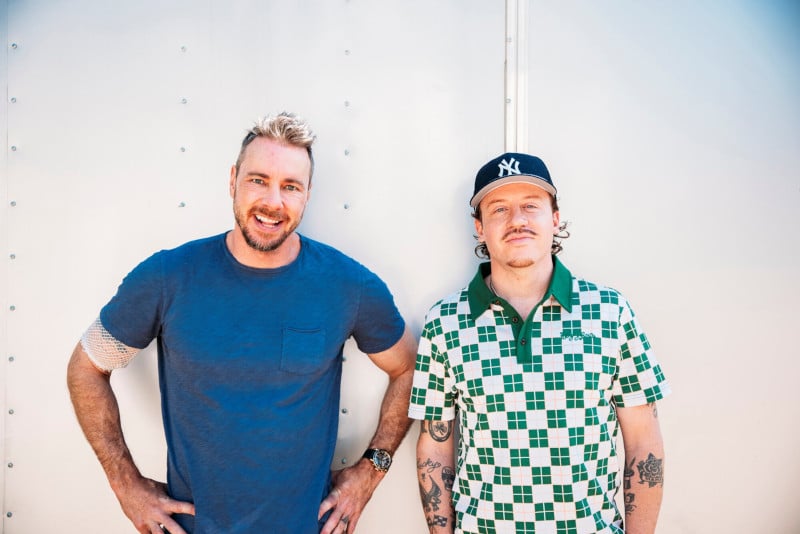 Blonde haired man in blue shirt (Dax) next to man in New York Yankees baseball cap wearing green and white checked shirt (Maclemore)