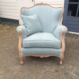 Antieke blauwe fauteuil met houten details en comfortabele kussens.