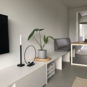 Alt tekst: Strak interieur met witte meubels, groene plant en zwarte accessoires in modern stadsappartement.
