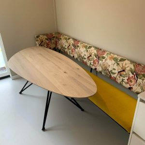 Alt: Eettafel met houten blad en zwart metalen poten, vintage bank met bloemenprint en gele stof.