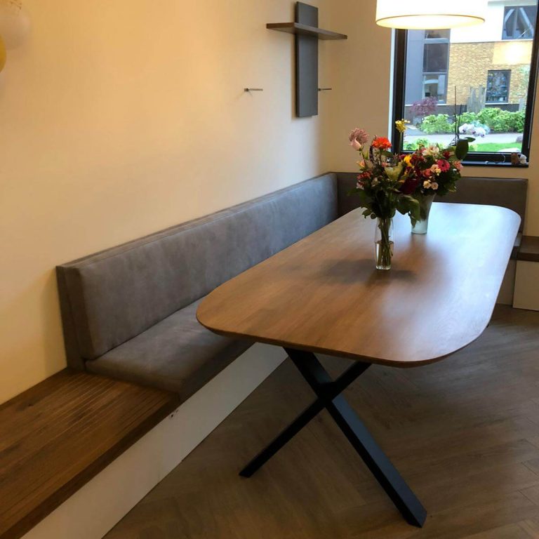 Een stijlvolle houten eettafel met bloemen in een heldere woonruimte, benadrukt de harmonie tussen oud en nieuw.