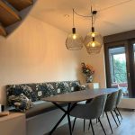 Moderne eetkamer met elegante hanglampen, eettafelbank op maat gemaakt, comfortabele stoelen en een grote tafel voor gezellige maaltijden.