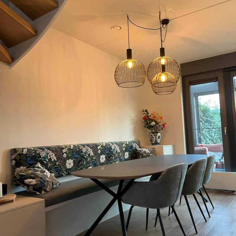 Moderne eetkamer met elegante hanglampen, eettafelbank op maat gemaakt, comfortabele stoelen en een grote tafel voor gezellige maaltijden.